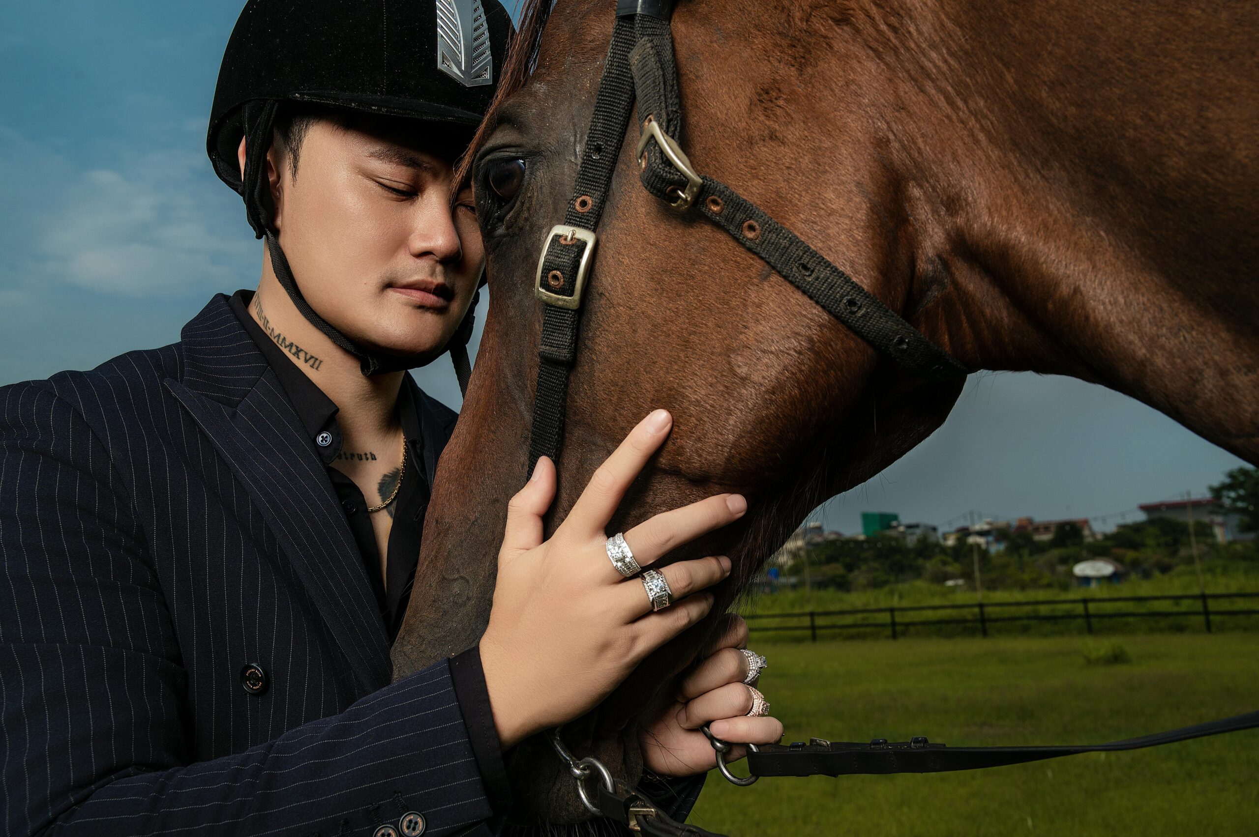 A young man in a helmet gently embracing a horse outdoors. Serene connection with nature.